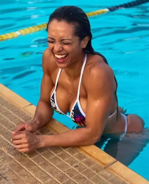 AI Video from prompt: She climbs out of the pool, laughs, and smooths 