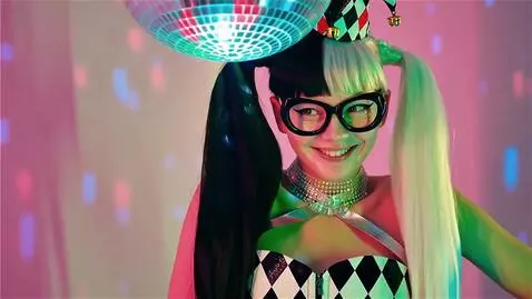 AI Video from prompt: “A playful, dorky Harlequin girl stands under ne