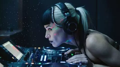AI Video from prompt: Profile shot of the Harlequin DJ woman with her 