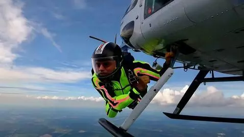 AI Video from prompt: A skydiver in a bright neon jumpsuit and helmet 