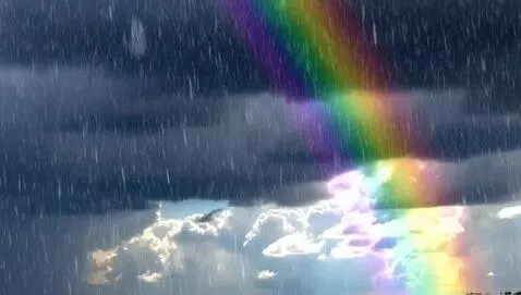 AI Video from prompt: A bright beautiful rainbow beams through dark th