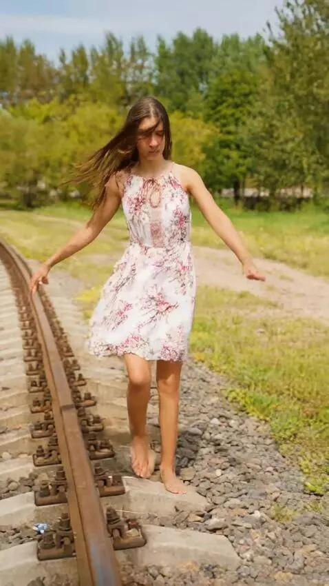 AI Video from prompt: A girl walks barefoot along the railroad tracks,
