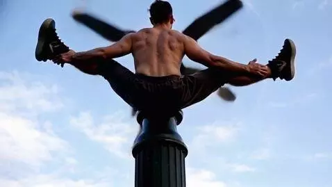 AI Video from prompt: A man with his ass on a lamppost spins like a pr