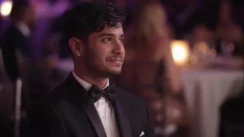 AI Video from prompt: парень в парадной одежде  сидит грустит но не по