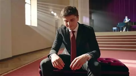 AI Video from prompt: парень в парадной одежде  сидит грустит но не по