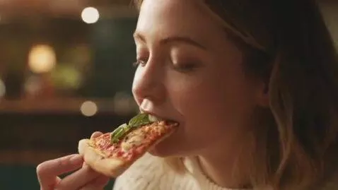 AI Video from prompt: a young blonde woman eating a slice of pizza