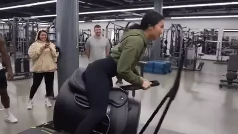 AI Video from prompt: A woman jumps onto a mechanical equestrian simul