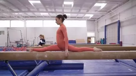 AI Video from prompt: Gymnast in an orange leggings in a high leg high