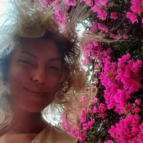 AI Video from prompt: A woman stands near a wall of vibrant pink bouga