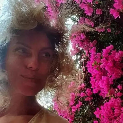 AI Video from prompt: A woman stands near a wall of vibrant pink bouga
