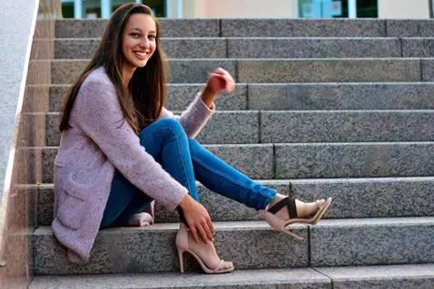 AI Video from prompt: Young woman smiles and lifts her left leg, showc