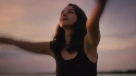 AI Video from prompt: A girl in a black dress is sitting on the riverb