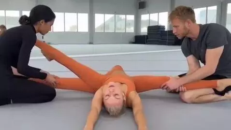 AI Video from prompt: Gymnast A lies on her back on the ground.  She h