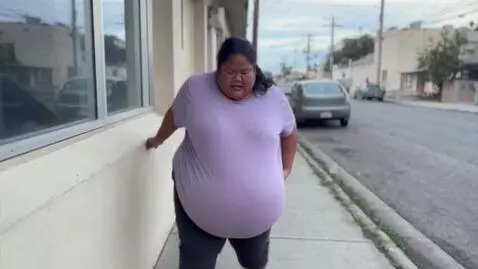 AI Video from prompt: A large, Filipina, ssbbw who is struggling to wa