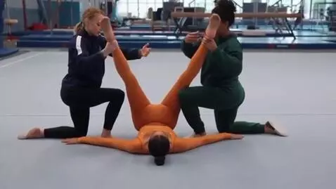 AI Video from prompt: Gymnast A lies on her back on the ground, her up