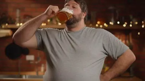 AI Video from prompt: hairy man drinks beer and his belly becomes bigg