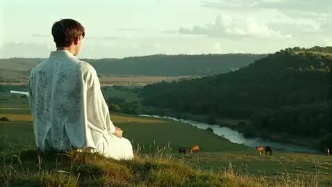 AI Video from prompt: A young man sits on a hill in a calm, motionless