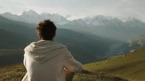 AI Video from prompt: A young man sits on a hill in a calm, motionless