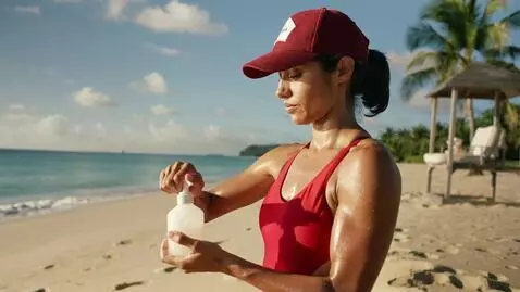 AI Video from prompt: Female life guard putting oil on her body