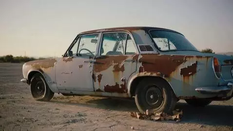 AI Video from prompt: Scene: A shabby, old car covered in dirt in a du