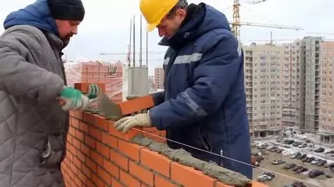 AI Video from prompt: Slavic-looking workers lay bricks on a residenti