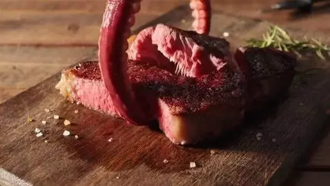 AI Video from prompt: Two red tentacles grab steak on wooden table, an