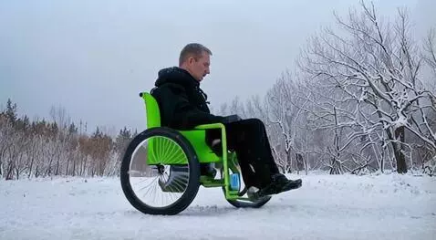 AI Video from prompt: In winter, a man rides a green electric wheelcha
