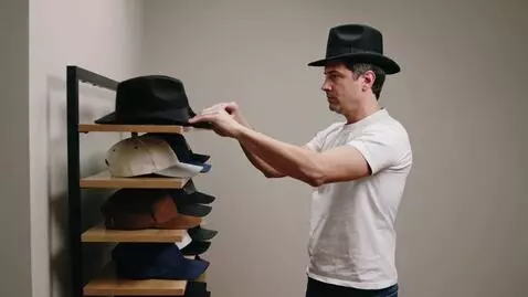AI Video from prompt: A man tries on various hats, such as a  top hat,