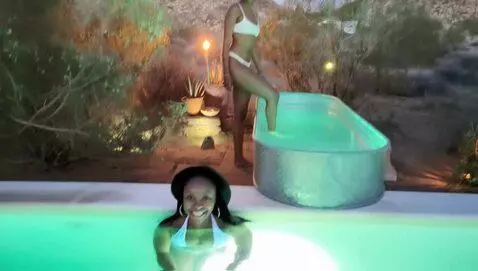 AI Video from prompt: the model steps into the outdoor bath and sits i