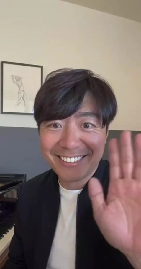 AI Video from prompt: Warm smile, gentle right-hand wave toward the ca
