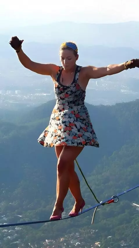 AI Video from prompt: an akrobat walks on a tightope over a chasm, and