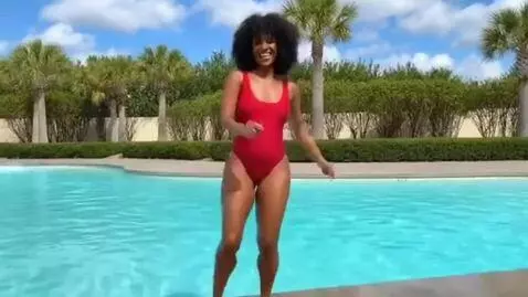 AI Video from prompt: Woman in wet red swimsuit dancing at edge off sw