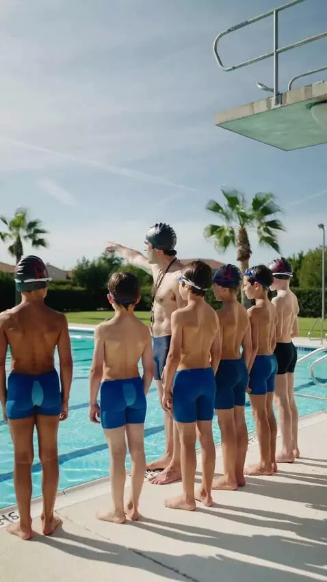 AI Video from prompt: Ten-year-old swimmers in swimming trunks stand i