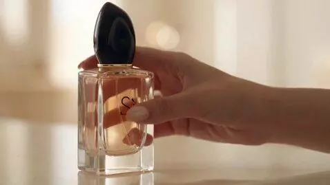 AI Video from prompt: The girl takes the perfume and sprays it on her 
