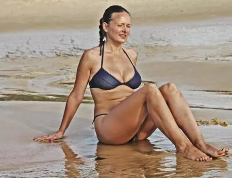 AI Video from prompt: a woman sitting on the sand straightens up and r