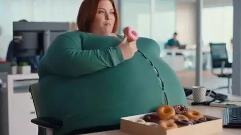 AI Video from prompt: a woman in an office eats donuts and becomes imm