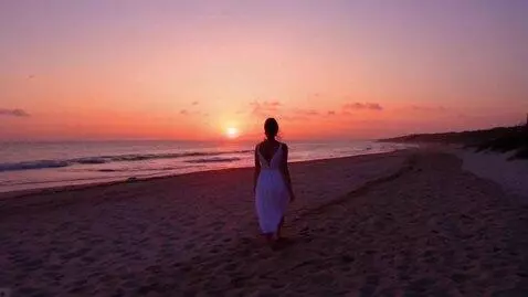 AI Video from prompt: Woman walking in the beach with sunset backgroun