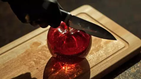 AI Video from prompt: A hand slices through a crisp red apple on a woo