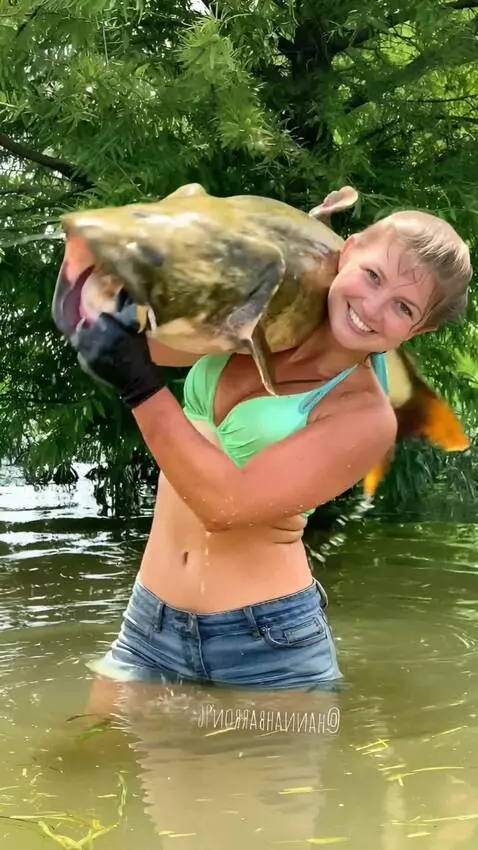 AI Video from prompt: A girl is  holds a huge catfish,which wriggles, 