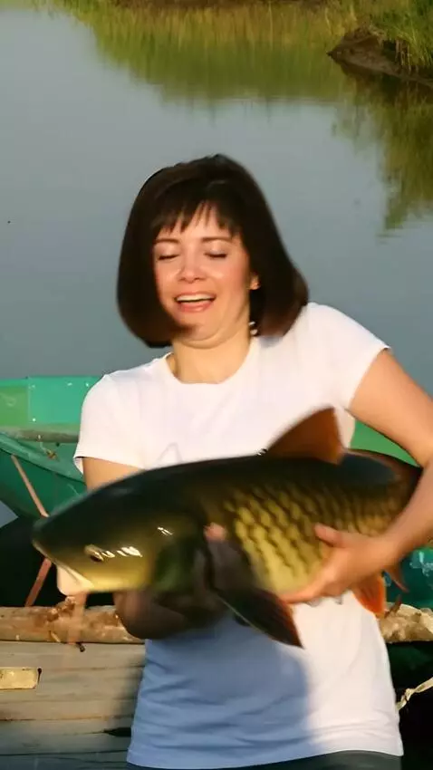 AI Video from prompt: A girl is  holds a huge catfish,which wriggles, 