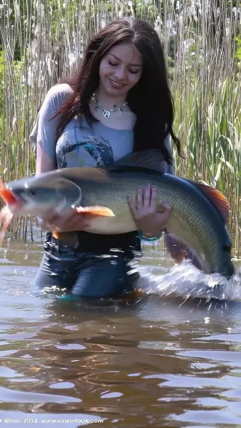 AI Video from prompt: A girl is  holds a huge catfish,which wriggles, 