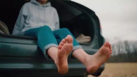 AI Video from prompt: A barefoot adult girl sits in the open trunk of 
