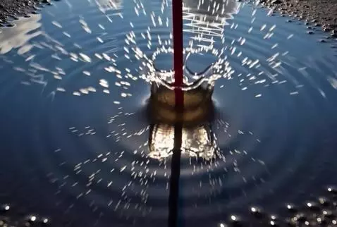 AI Video from prompt: A drumstick strikes the surface of a puddle that
