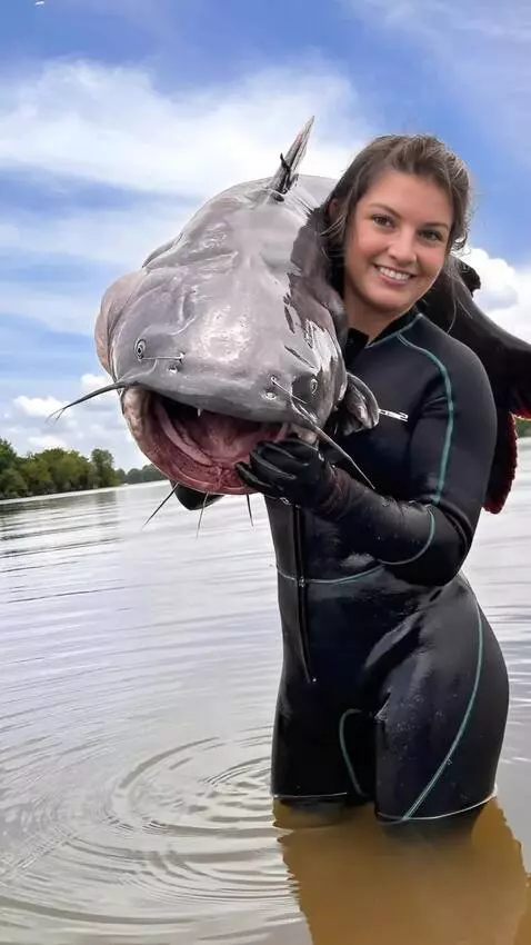 AI Video from prompt: The girl tries to hold the wriggling catfish, bu