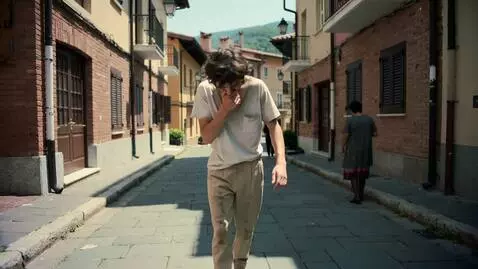 AI Video from prompt: A messy young man walking through a small town s