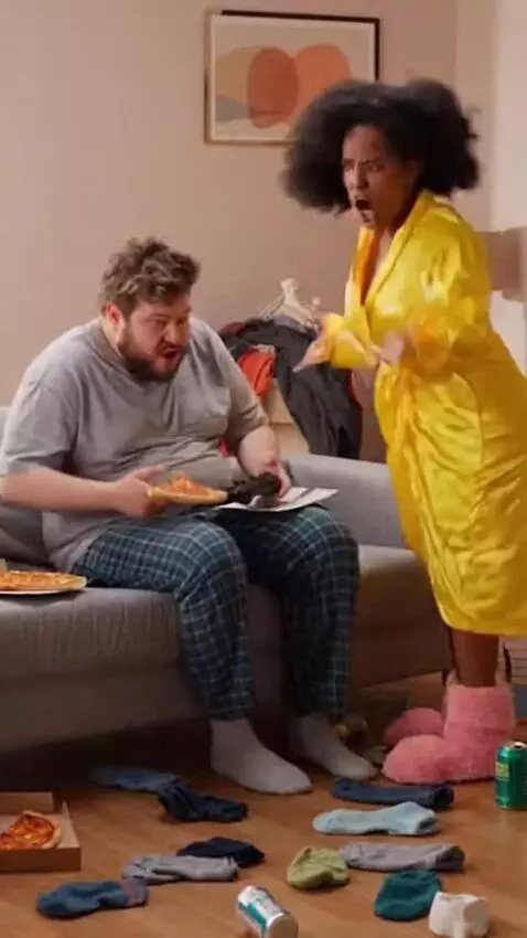 AI Video from prompt: A comedic skit: a lazy husband sits in a clutter