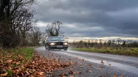 AI Video from prompt: the Rolls Royce drives through the rain in the E