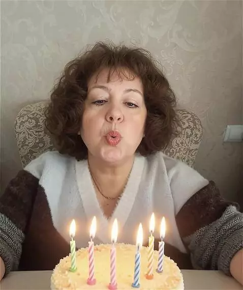 AI Video from prompt: A woman happily blows out candles on a cake