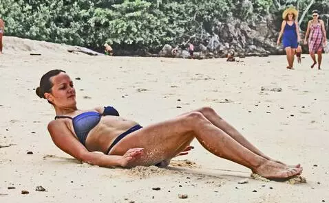 AI Video from prompt: A woman sitting on the beach with her legs curle