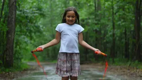 AI Video from prompt: Cute girl jumping rope in the woods while it rai